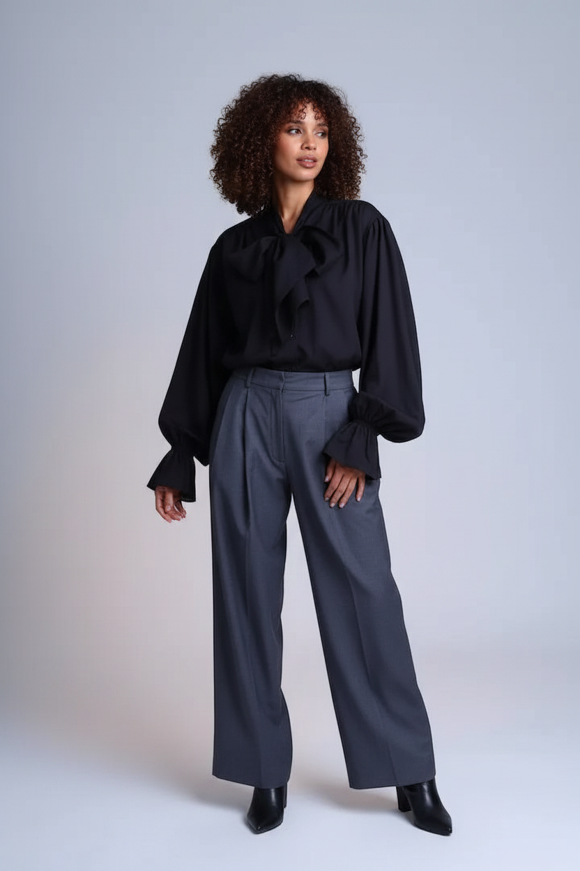 Woman wearing black Tencel blouse with bow-tie neckline and voluminous sleeves in editorial studio setting