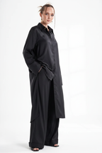 Woman wearing deep black matching set with maxi button-down shirt and palazzo pants in editorial studio setting